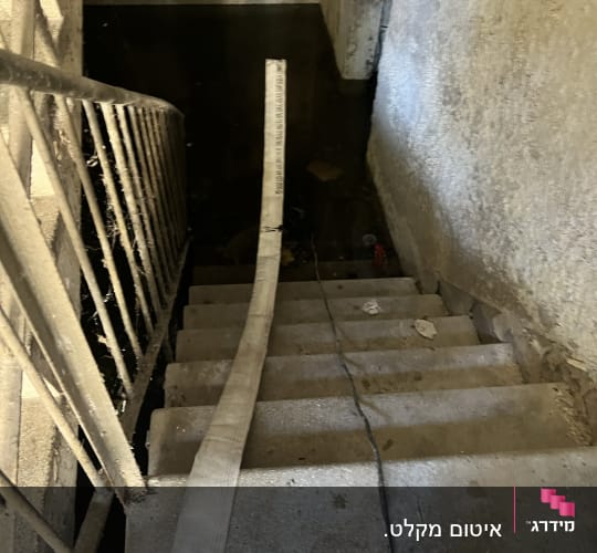 צינור על מדרגות ליד מים עומדים במרתף